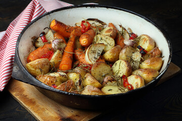 Oven baked potatoes, carrots, garlic, onions with chili, thyme and rosemary