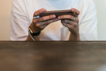 select focus mobile phone brown In his hand is a man wearing a white shirt. Playing a game and plugging in the battery charger with space for the text below the image.