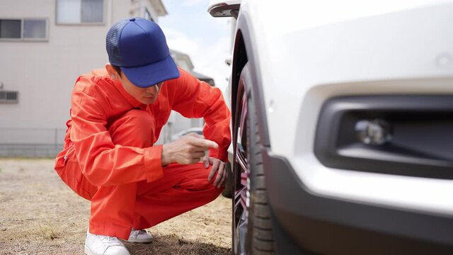 自動車のタイヤを点検する男性整備員
