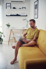 Man working on a laptop from the living room. Work from home concept.