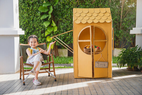 Children playing with little paper cafe at home. Asian little child girl with her cardboard house. children were painting,drawing on the house made of paper. STEAM education
