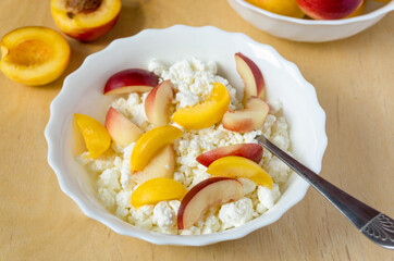 Cottage cheese with nectarine in white bowl on wooden background