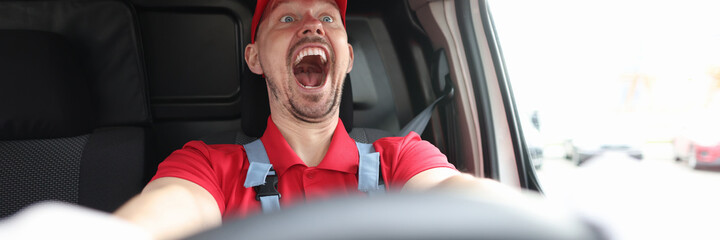 Happy male courier riding behind wheel of car with open mouth