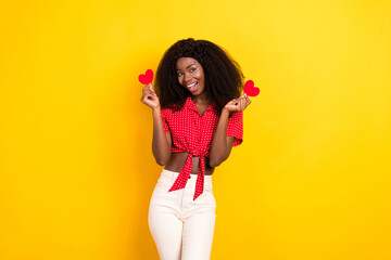 Portrait of attractive cheerful girl holding in hands small little heart shape isolated over bright yellow color background