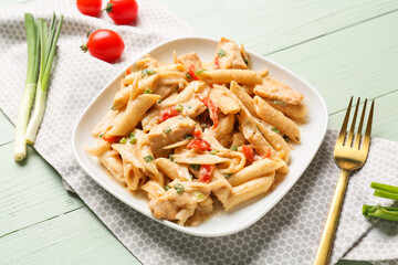 Plate with tasty cajun chicken pasta on color wooden background, closeup