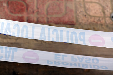 A diagonal red stop sign on a white plastic tape. Mirrored writing on a police barrier tape.