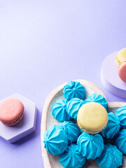Heart shaped wooden dish with blue sweet meringues and macaroons