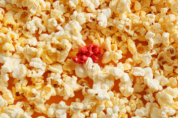 Pink popcorn among white ones on color background. Concept of uniqueness