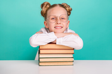 Photo of funny little girl with books wear white shirt spectacles isolated on teal background