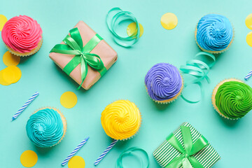 Tasty Birthday cupcakes, gifts, candles and ribbons on color background