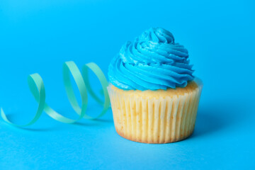 Tasty Birthday cupcake and ribbon on color background, closeup