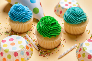 Composition with tasty Birthday cupcakes, party hat and candles on color background, closeup