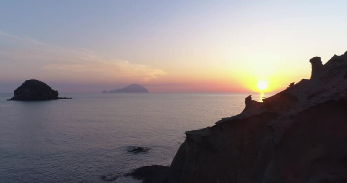 Time lapse of Salina coast in Aeolian islands during a summer sunset. Silhouette of Salina coast, blue and orange sky with clouds in background and sea during golden hour.