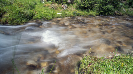a strong flow in a mountain creek with melting water from the alps in summer