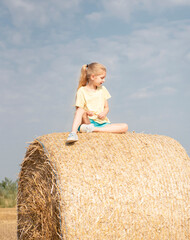 Naklejka na ściany i meble Little girl having fun in a wheat field on a summer day.