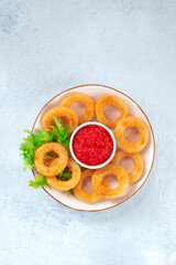 Calamari rings. Coated squid rings with ketchup and green salad, shot from the top