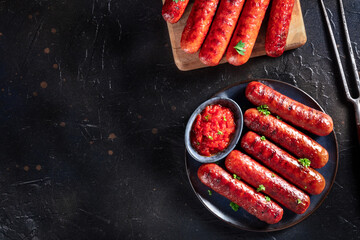 Grilled sausages, shot from above on a dark background with copy space. Delicious barbecue meal