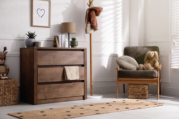 Stylish room interior with wooden chest of drawers and comfortable armchair - Powered by Adobe