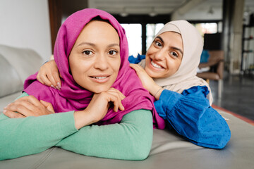 Two smiling muslim woman wearing hijab laying