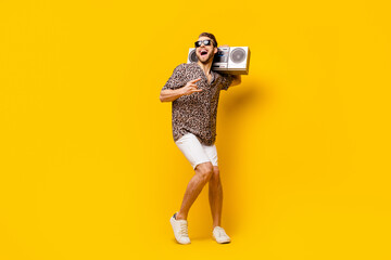 Full length photo of handsome cool gentleman dressed print shirt glasses showing hard rock sign boombox isolated yellow color background