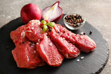 Board with raw beef meat on grey background, closeup