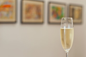 Glasses with wine on the background of the exhibition of paintings. Artwork blurred in the background. Art salon with white walls.