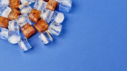 Frozen cola in cubes. Ice lies on a colored background with a place to copy, panoramic view,...