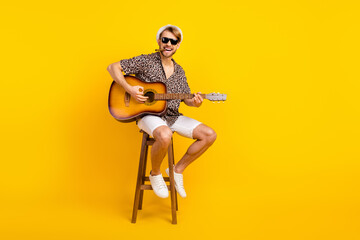 Fototapeta na wymiar Photo of handsome cute young guy wear leopard outfit dark eyewear cap smoking playing guitar isolated yellow color background