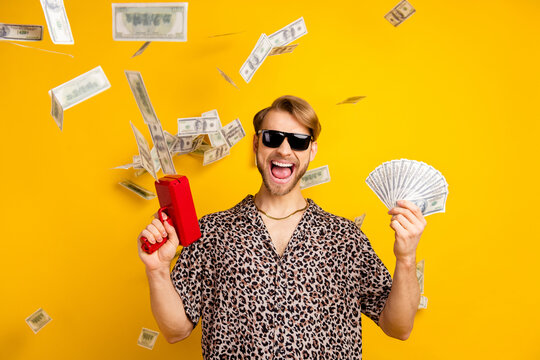 Photo of cool handsome young gentleman dressed print shirt dark glasses shooting money gun isolated yellow color background