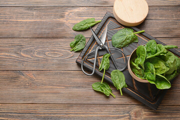 Box with fresh spinach leaves and scissors on wooden background