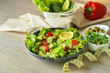 Plate of delicious salad with vegetables and measuring tape on wooden table