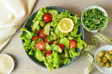 Plate of delicious fresh salad with vegetables and measuring tape on wooden table