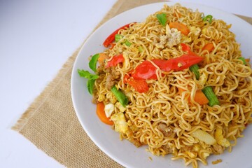 Mama noodles, delicious fried mama on a white plate on a brown sackcloth.