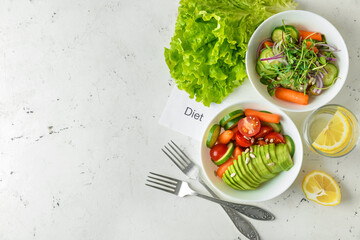 Bowls with delicious vegetable salad and paper sheet with word DIET on light background