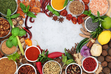 Herb and spice border with fresh, dried herbs, spices. Ingredients for gourmet cuisine. On mottled grey background with copy space.   Flat lay top view.