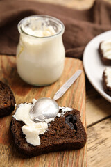 Delicious cream cheese and bread on wooden table