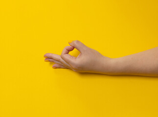 Fototapeta na wymiar Female hand with bright manicure shows ok sign on yellow background