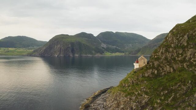Hendanes Lighthouse On Rugged Mountain Slope At The North Sea Coast In Maloy Region, Norway. aerial arc shot