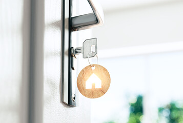 Key in the door with a house-shaped pendant. The concept of a new apartment was purchased from a developer