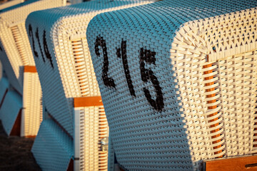 backs of Baltic Sea beach chairs with numbers in the morning sunlight 