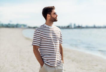 summer holidays and people concept - portrait of young man in sunglasses on beach in tallinn,...