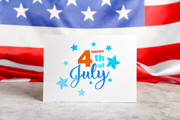 Greeting card for Independence Day on table against American flag