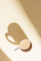 Cup of coffee with milk on beige with sunlight. Breakfast on sunny summer day.