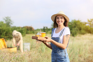Female beekeeper with sweet honey at apiary