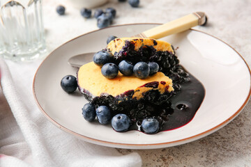 Plate with pieces of blueberry cobbler on light background, closeup