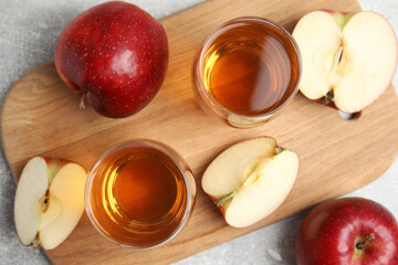 Delicious cider and ripe red apples on grey table, flat lay