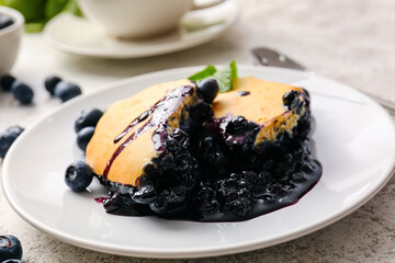 Plate with pieces of blueberry cobbler on light background, closeup