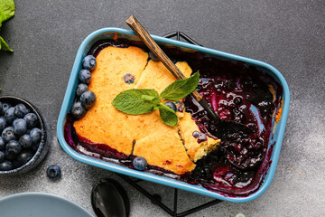Baking dish with blueberry cobbler on grey background
