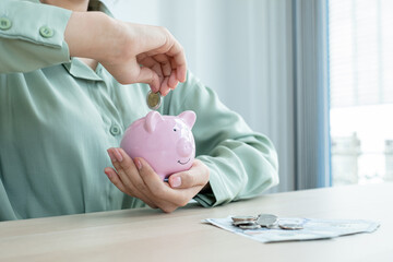 The hand of a businesswoman puts coins in a piggy bank, saves money with coins, steps into a...