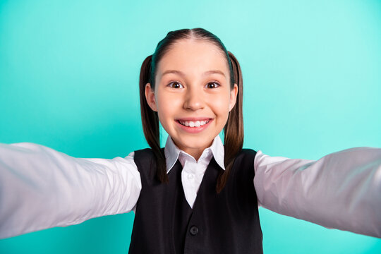 Photo portrait little girl in uniform smiling taking selfie isolated pastel teal color background